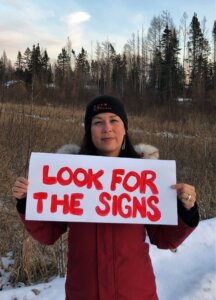 Harmony Redsky holding "Look For the Signs" poster