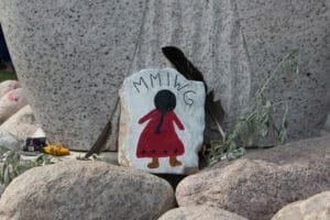 MMMIWG and girl in red dress painted on a rock