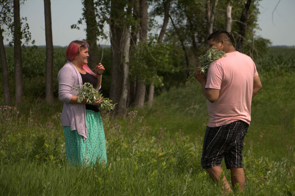 Two people gathering medicine and participating in Land-Based healing