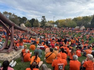 A large group of people wearing orange shirts gathered in a circle